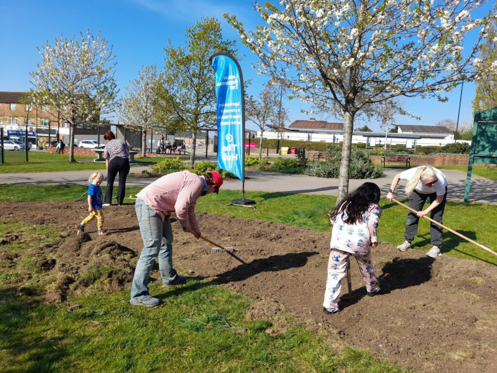 Description: Three women and two children rake over soil on Gainsborough Square