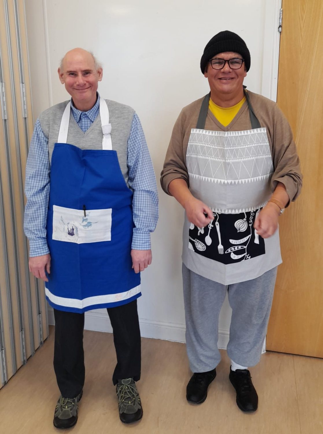 Two men in their 50s with aprons on smiling