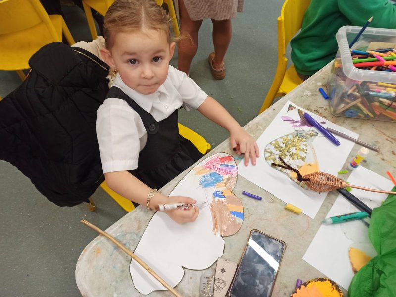 a child drawing on a paper butterfly