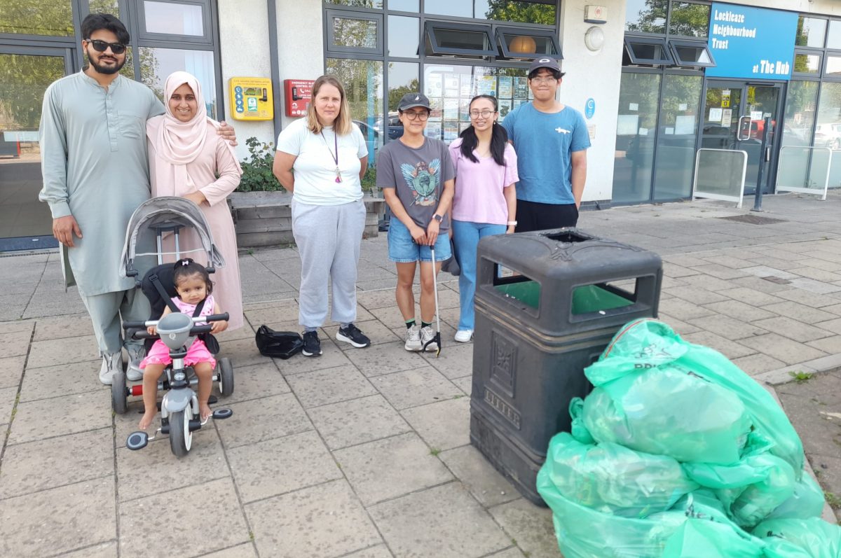 A family with a buggy and four other people stand proudly with a pile of rubbish bags.