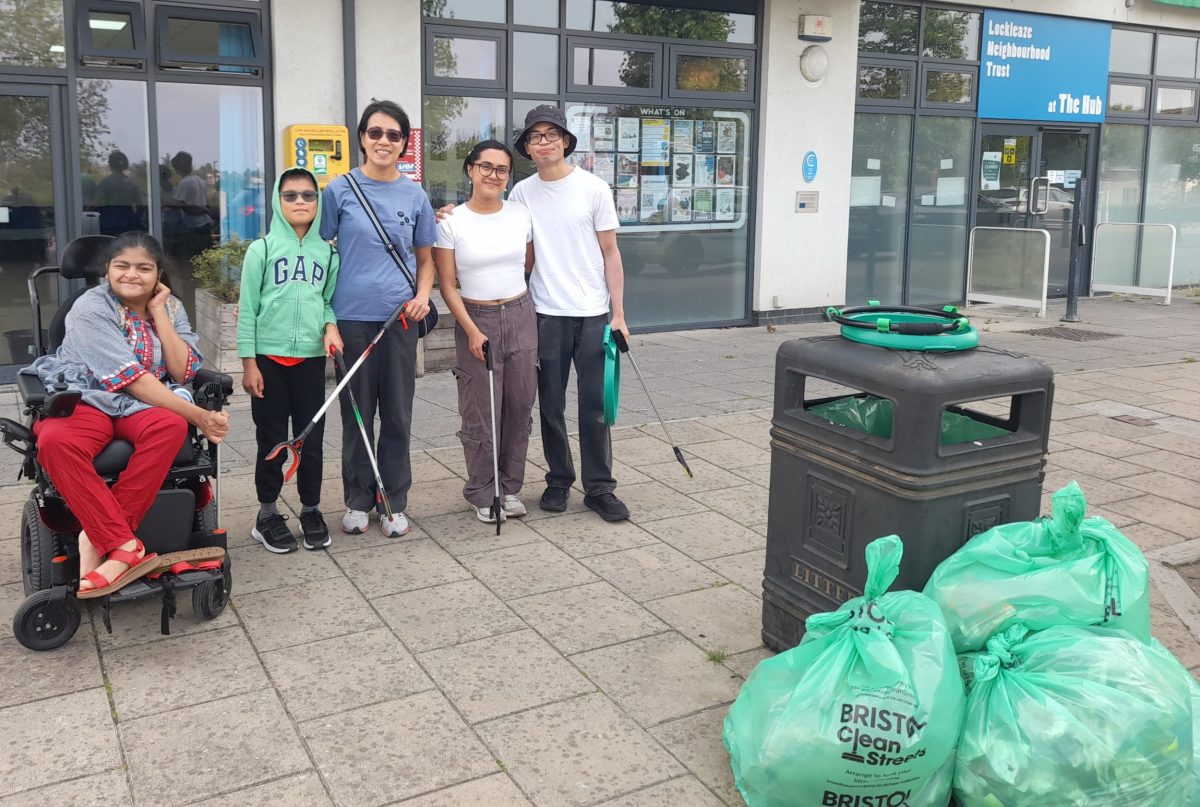 Five people, one using a powered wheelchair, smile with litterpickers