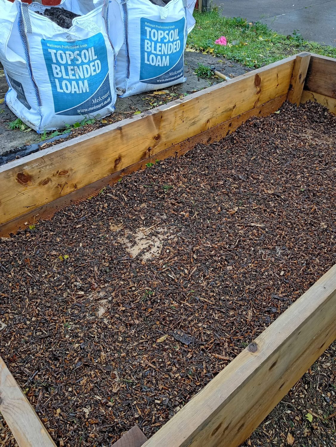soil in a raised bed with topsoil sacks behind