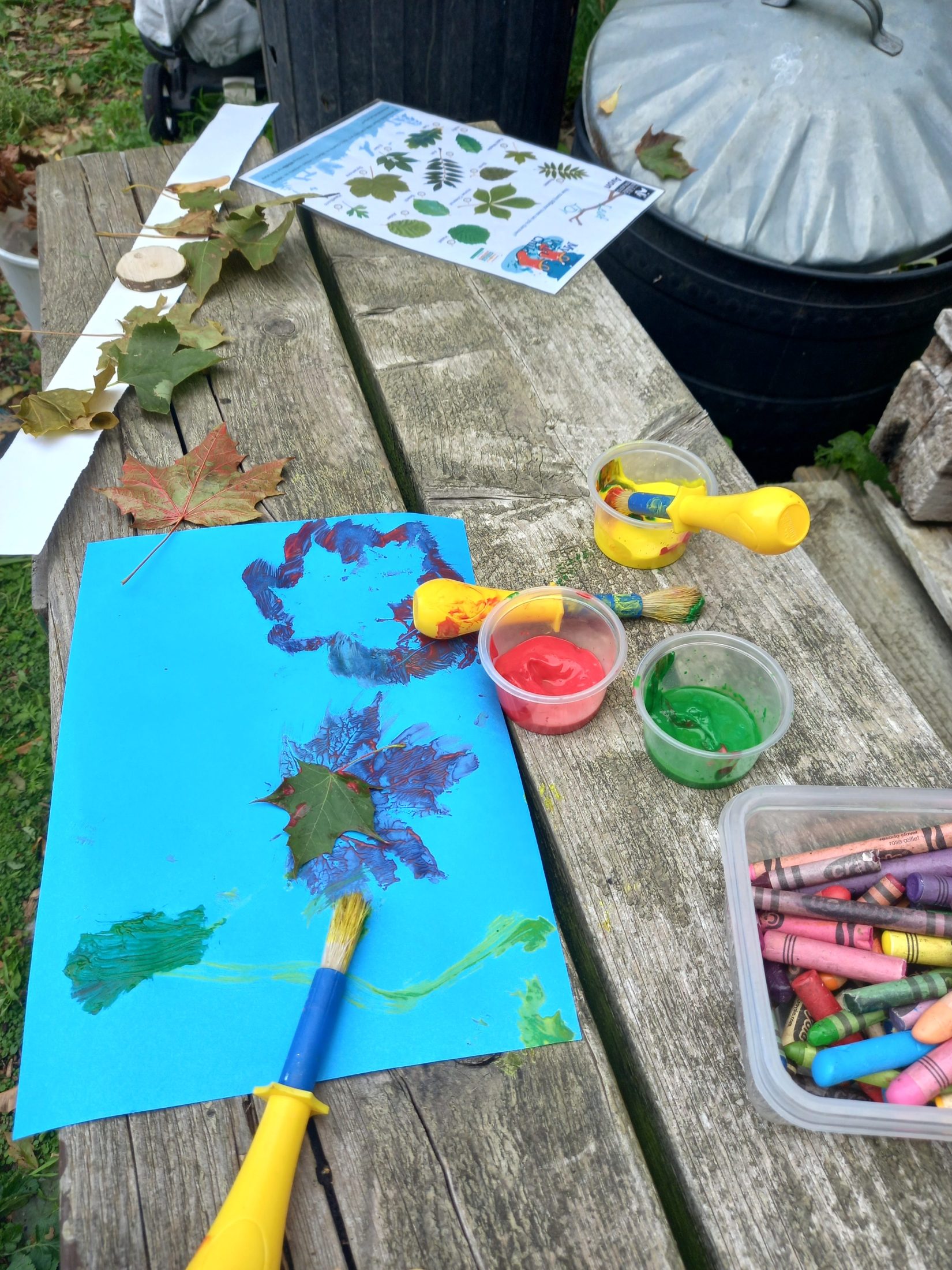 crayons, paint and card on an outdoor wooden table
