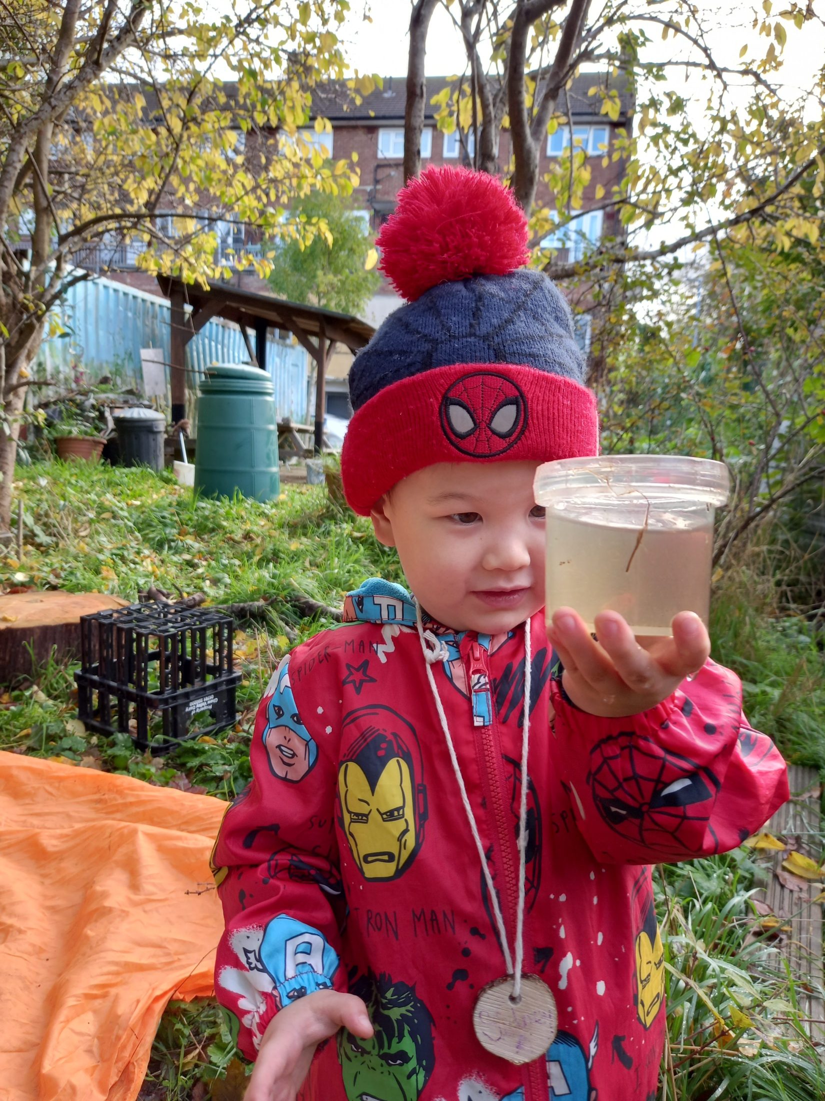a small boy holds up a tub with an insect in