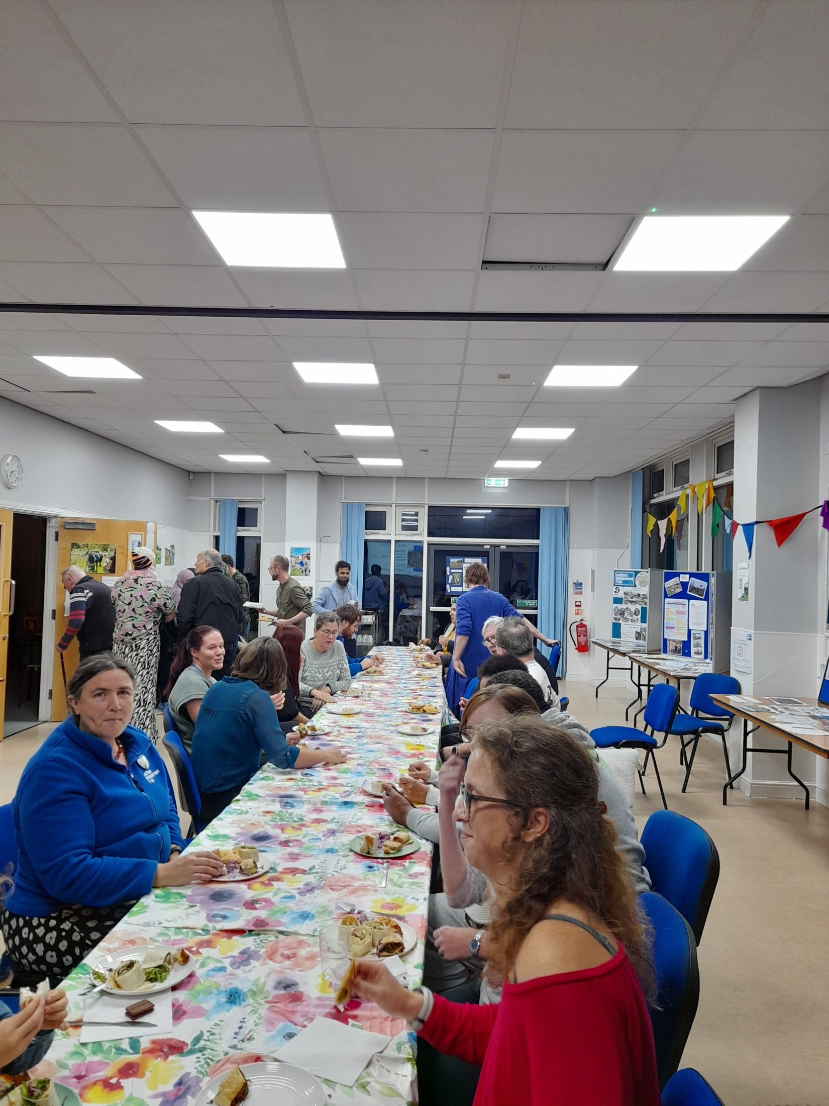 people sit along a long table with food