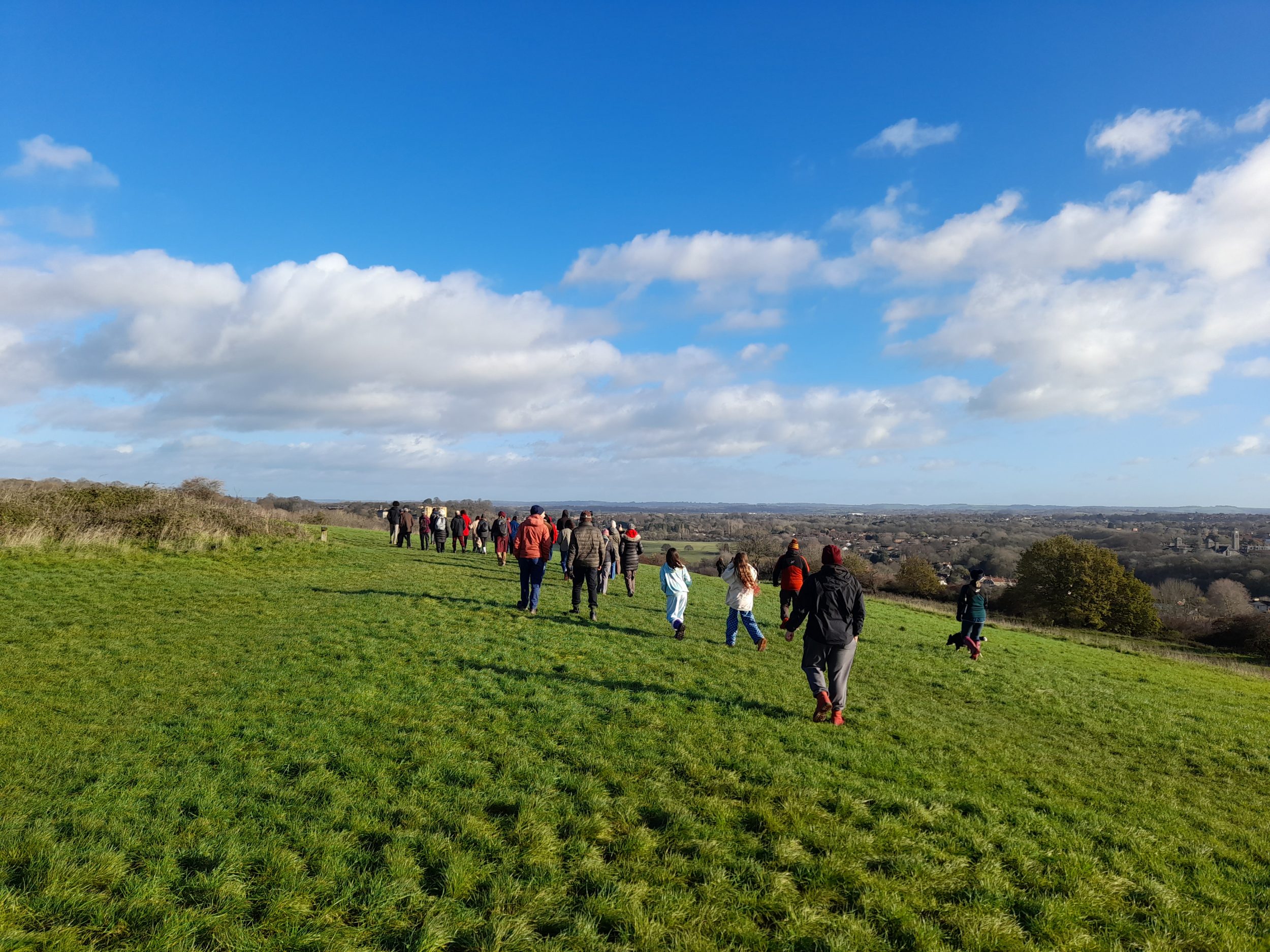 people walk across a hill on a sunny day