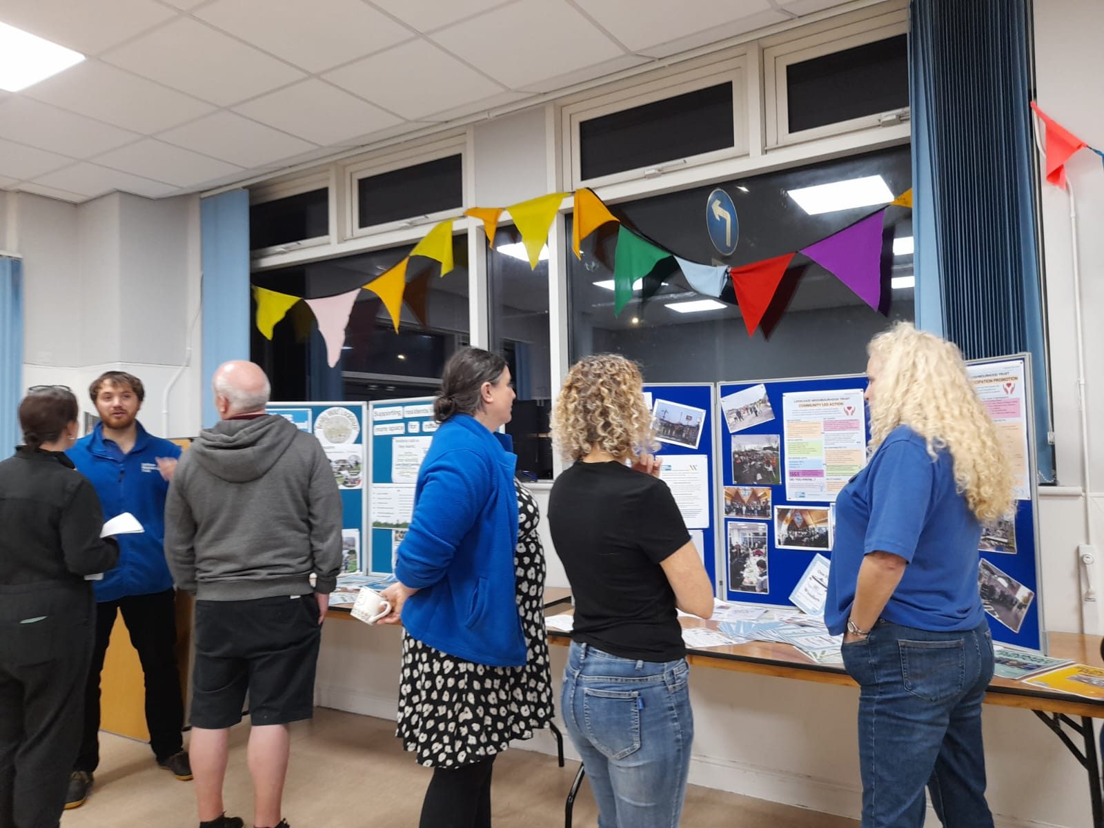 three LNT staff and three people chat looking at three blue boards of information on really wild lockleaze and community action