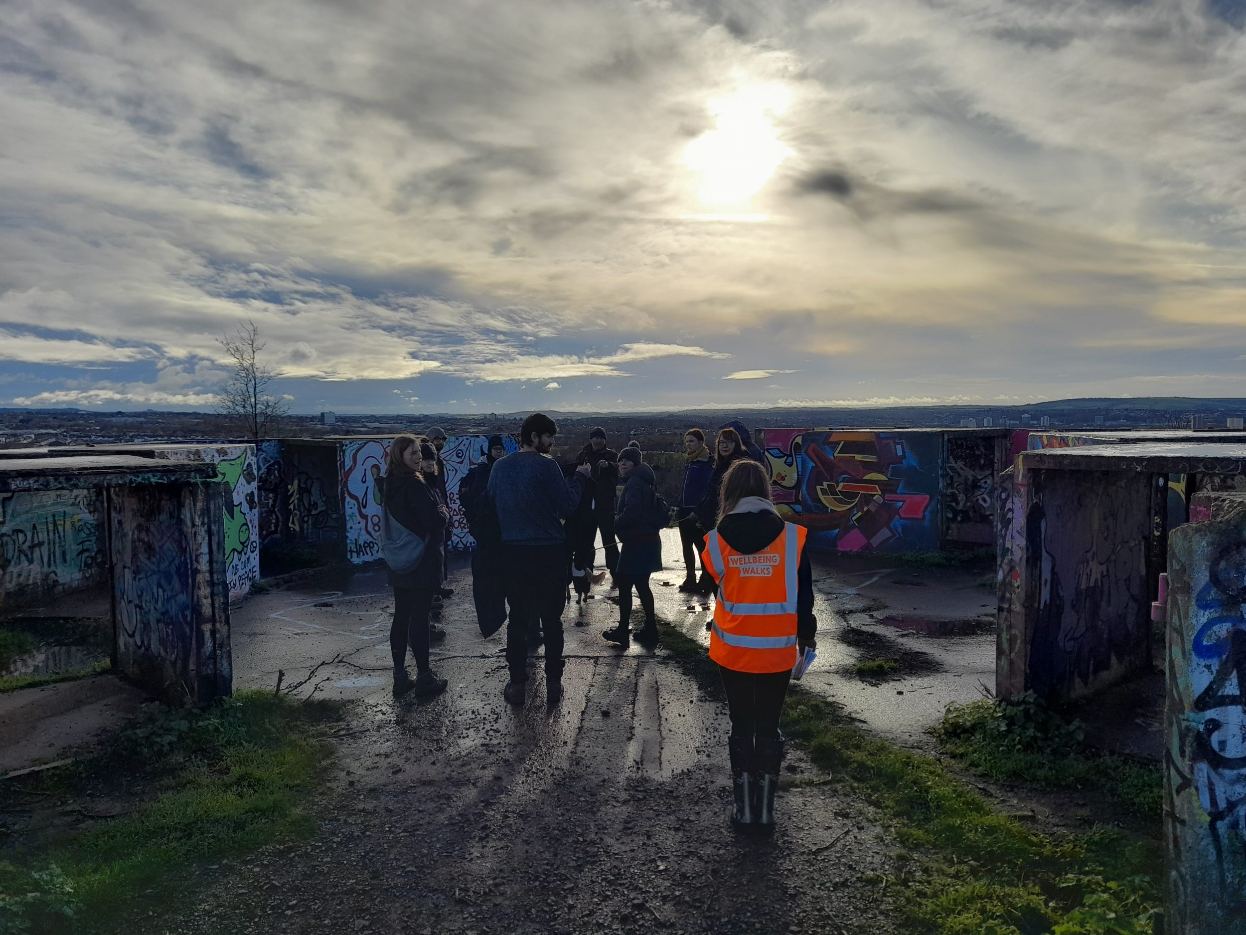 a dramatic dark sky with light coming through onto a group of walkers
