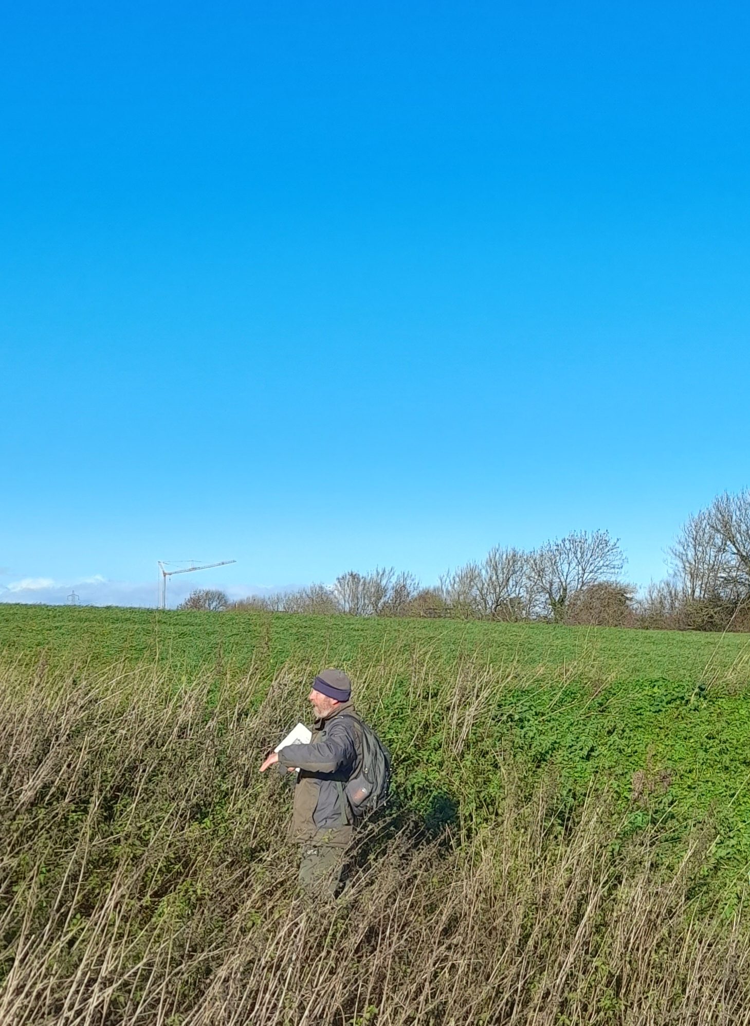 steve england, a white man in outdoor gear stands in a patch of long grass