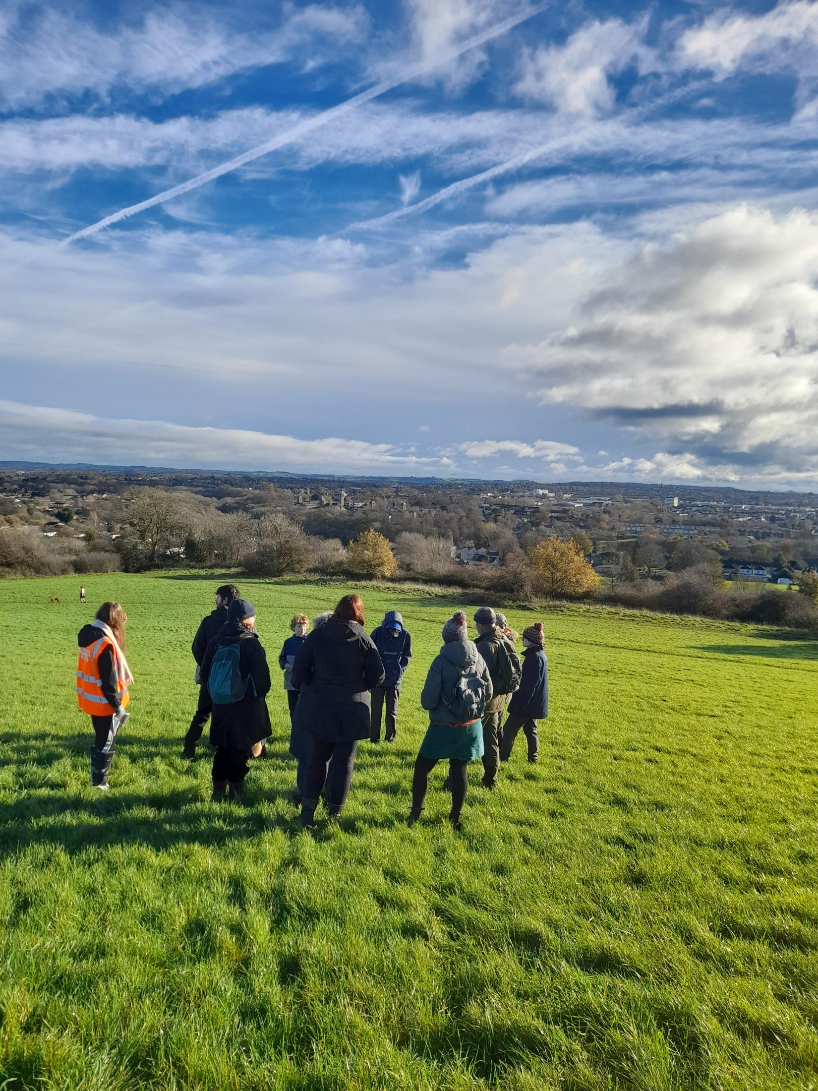 walkers on the hill with bristol in the background. there are beautiful wispy clouds.