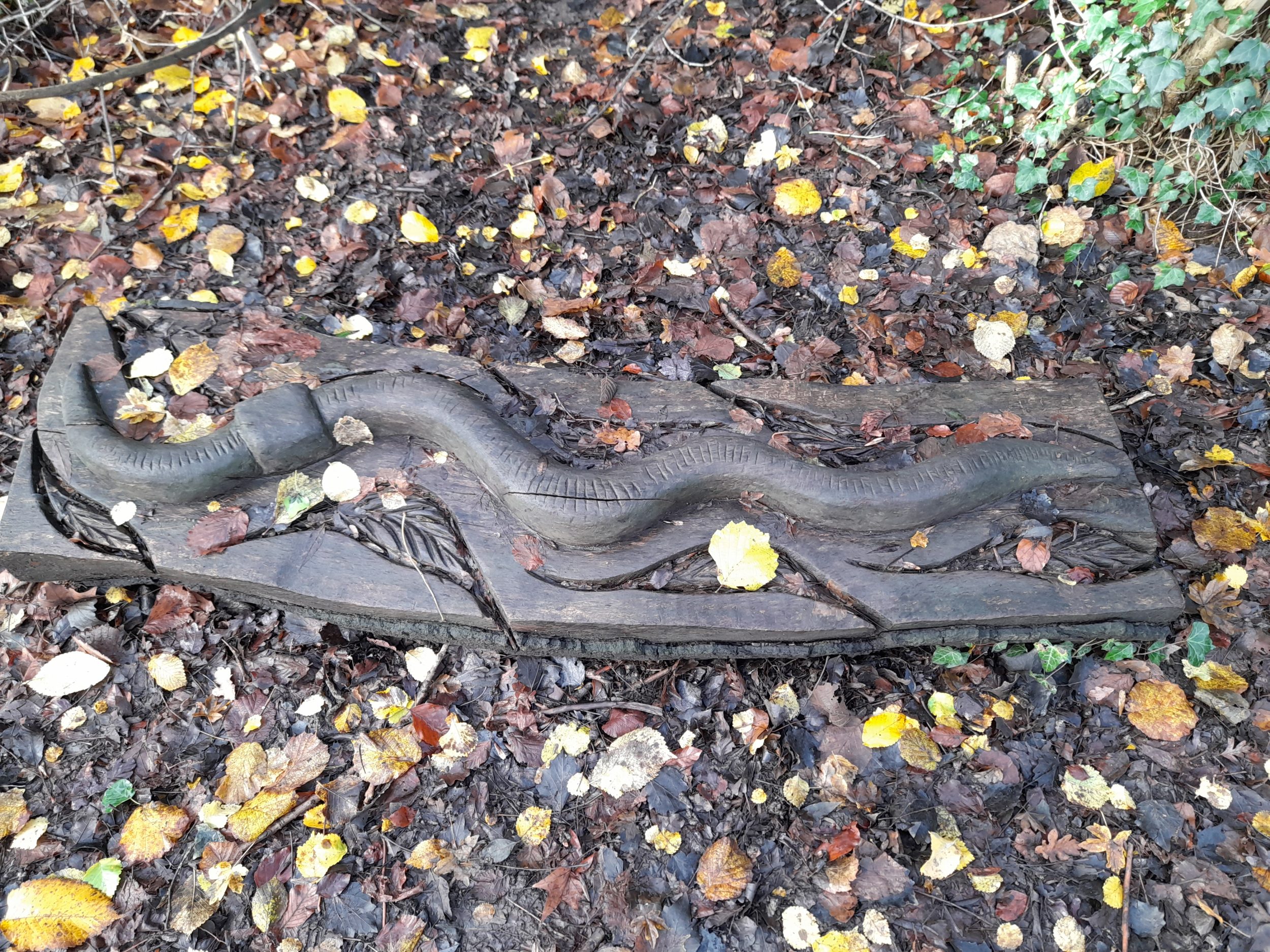 a wooden sculpture of a worm on the ground