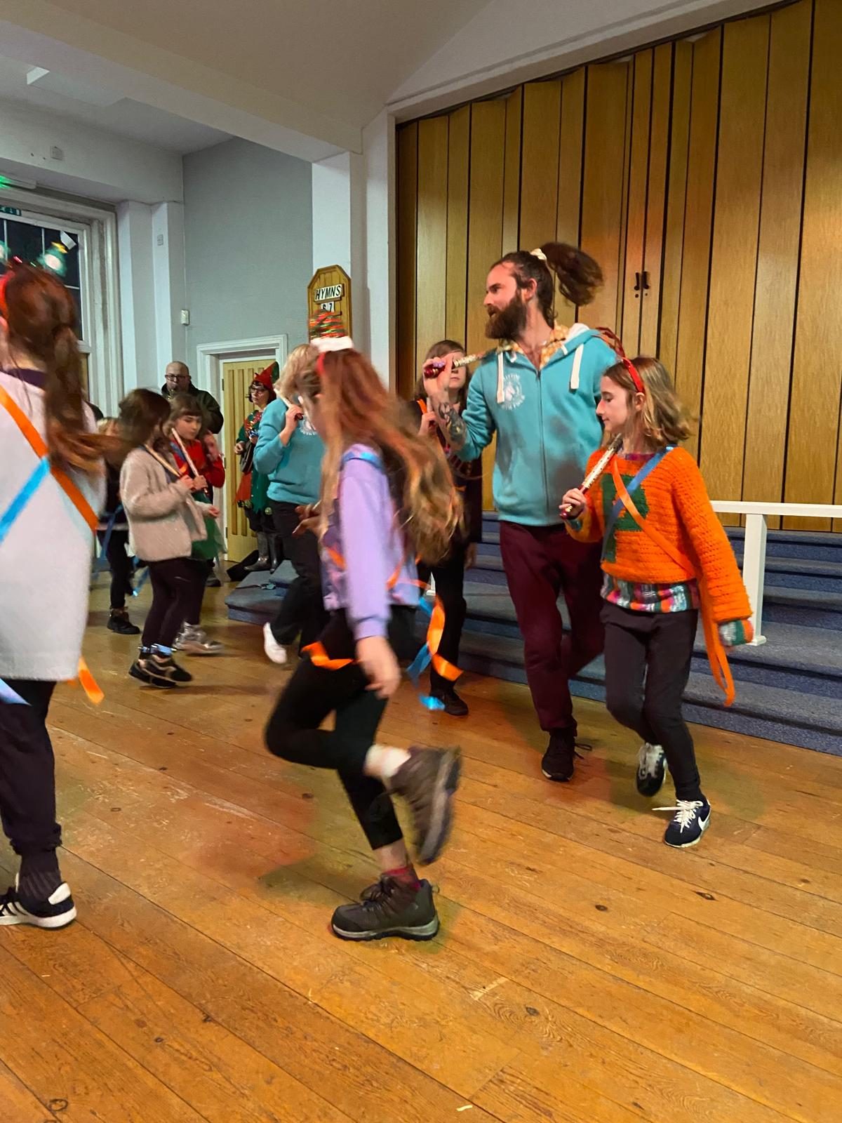 children and one adult jump in the air whirling hankies