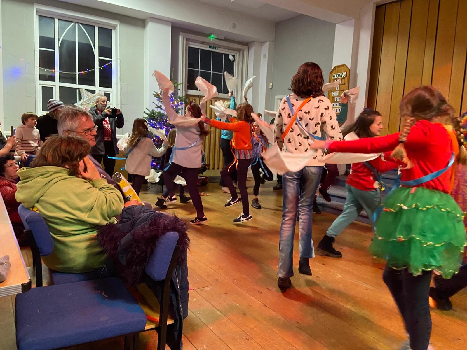 children in blue and orange ribbon whirl around with hankies