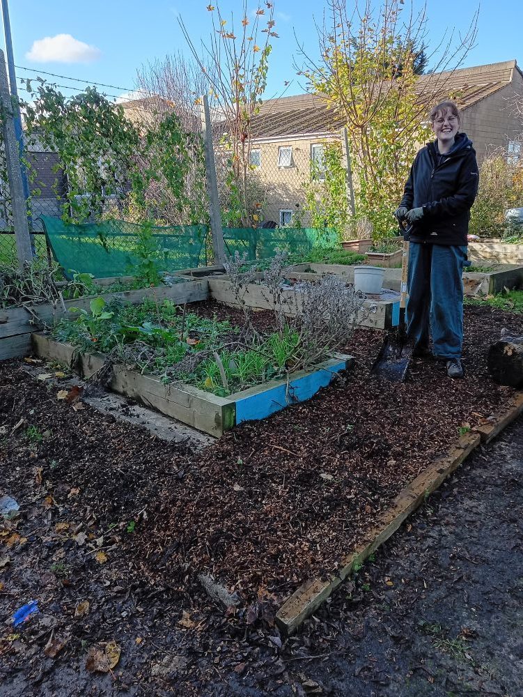 a young woman stands next to a raised bed