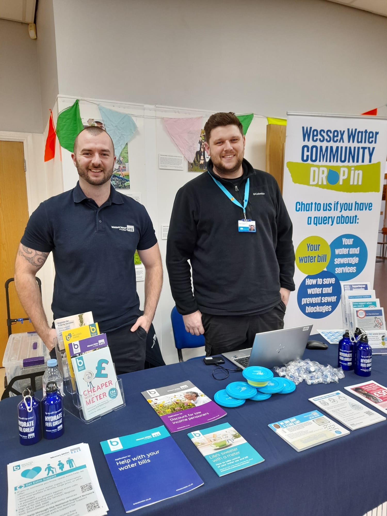 two smiling men behind a desk laid with materials related to wesssex water