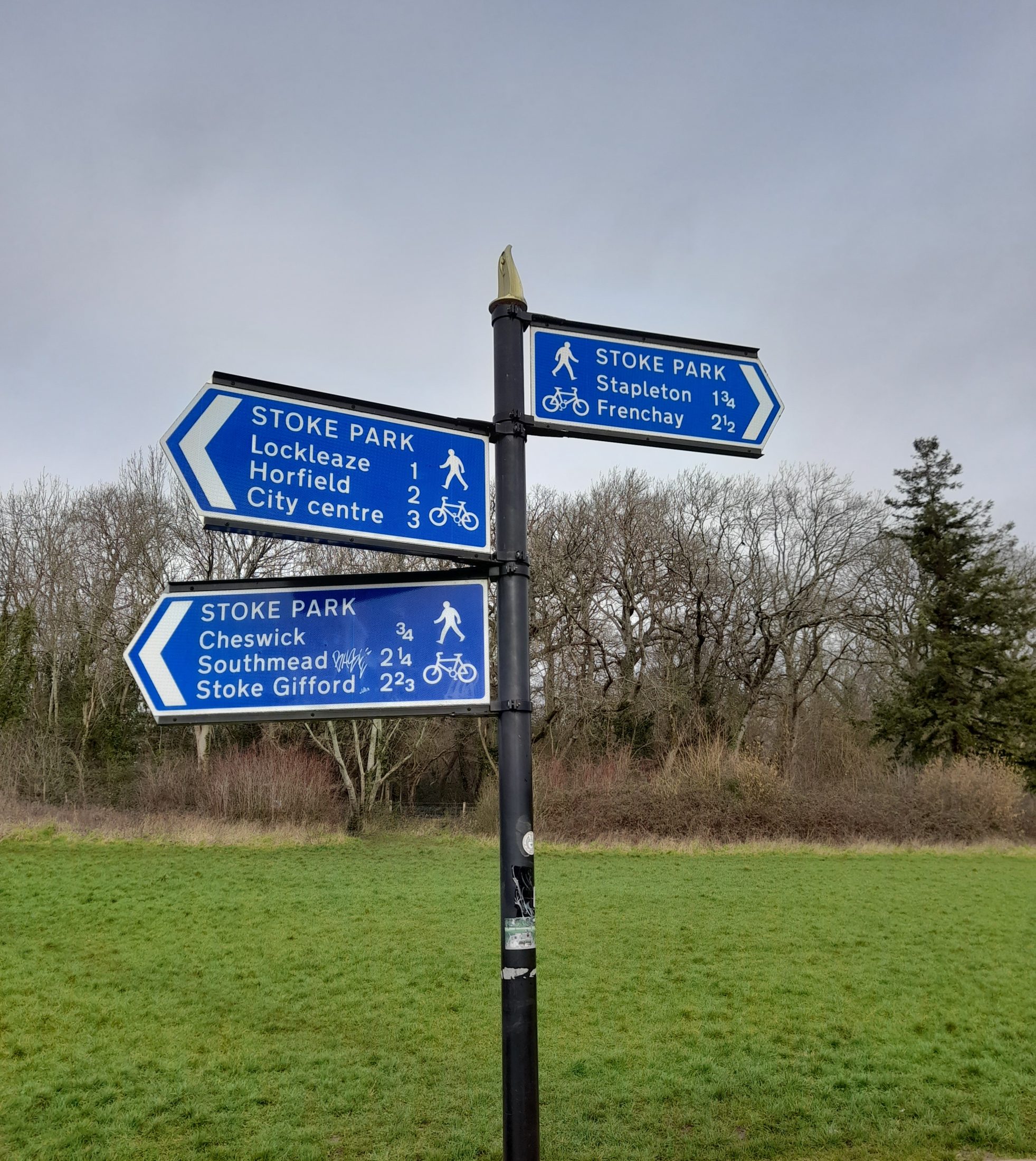 a lack signpost with three blue directional signs, pointing to Lockleaze (1), Horfield (2), Stapleton (1 3/4) etc