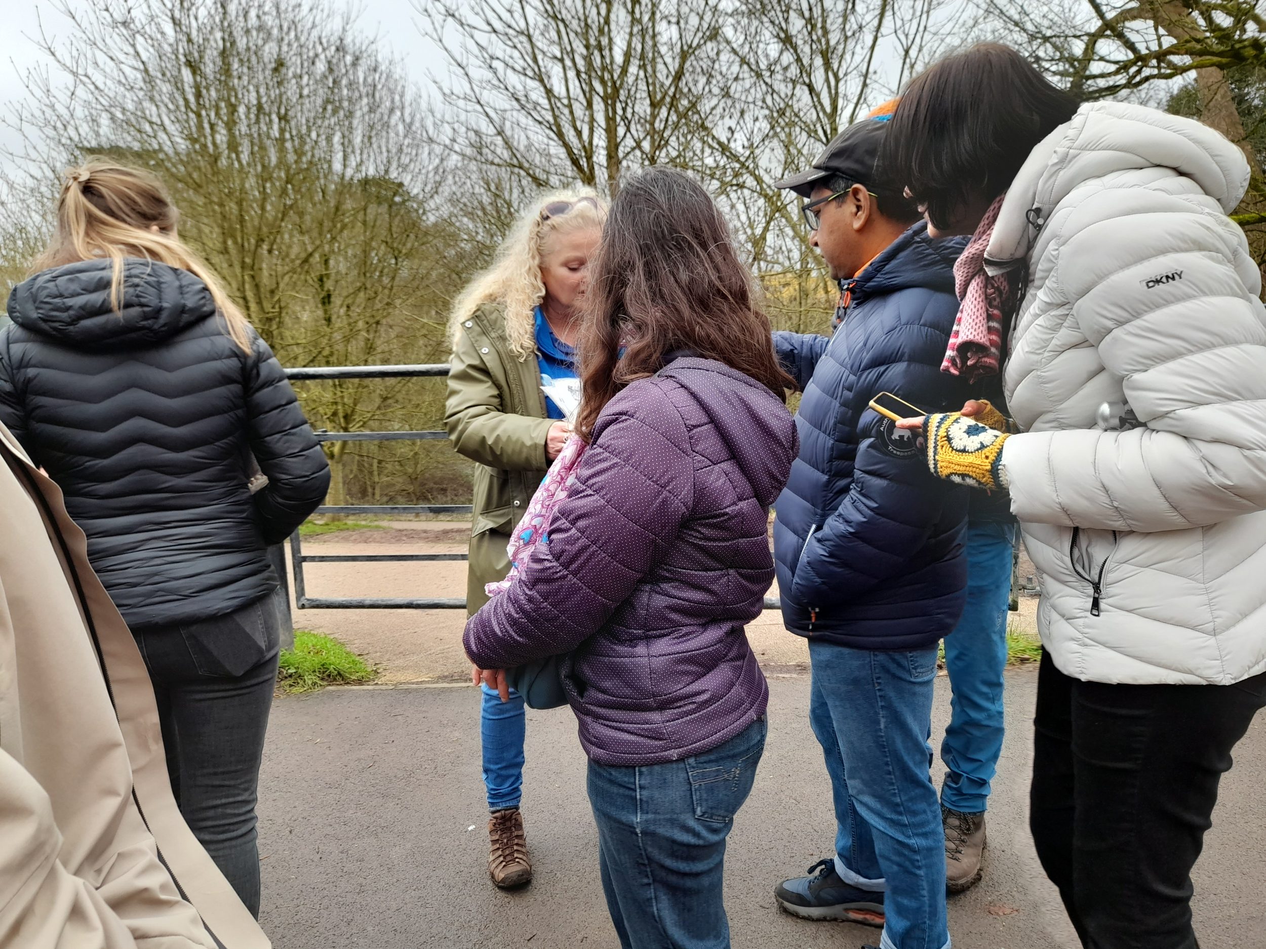 a blonde woman shows a picture (image not visible) to several walkers
