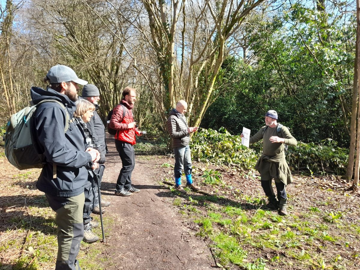 steve, a white man in his 50s, shows a photo to walkers in a woodland