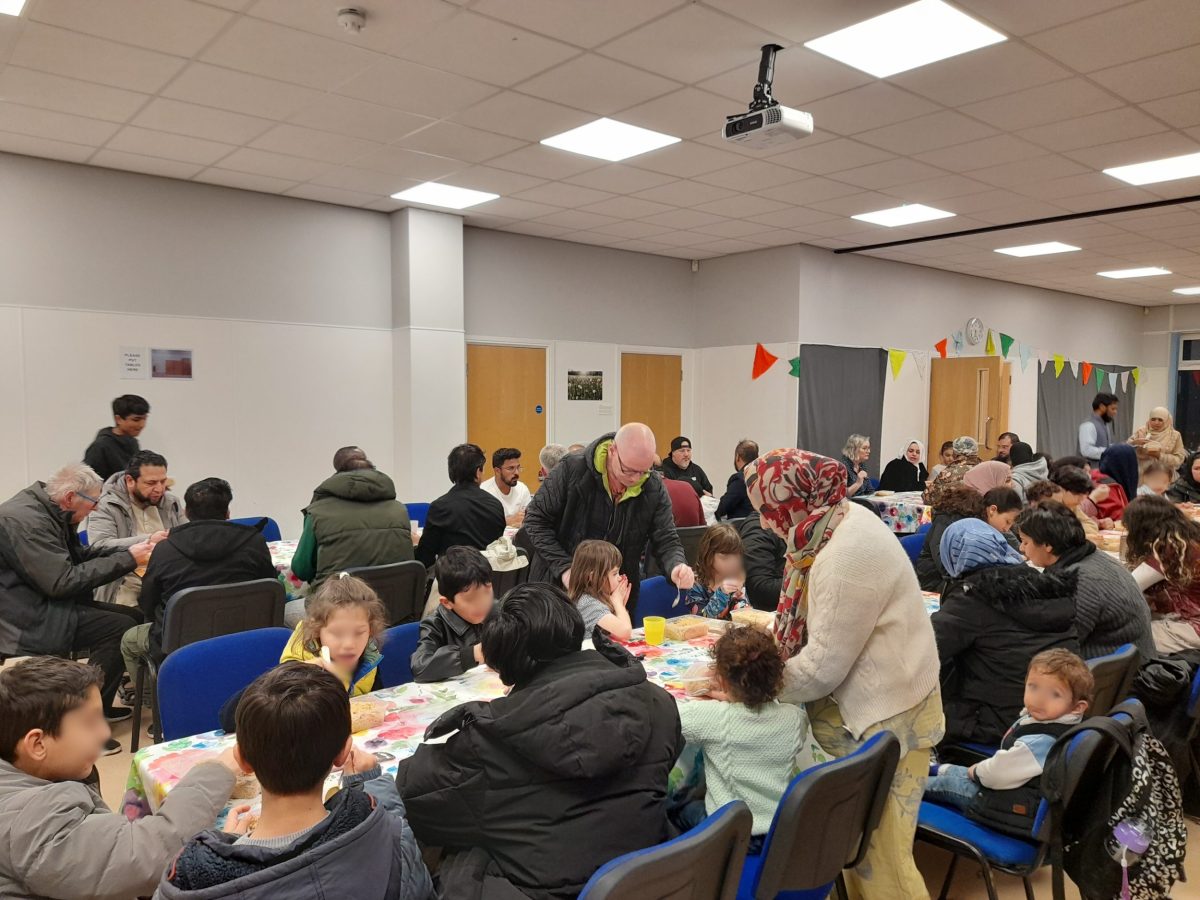 a table with lots of children of multiple ethnicities eating together