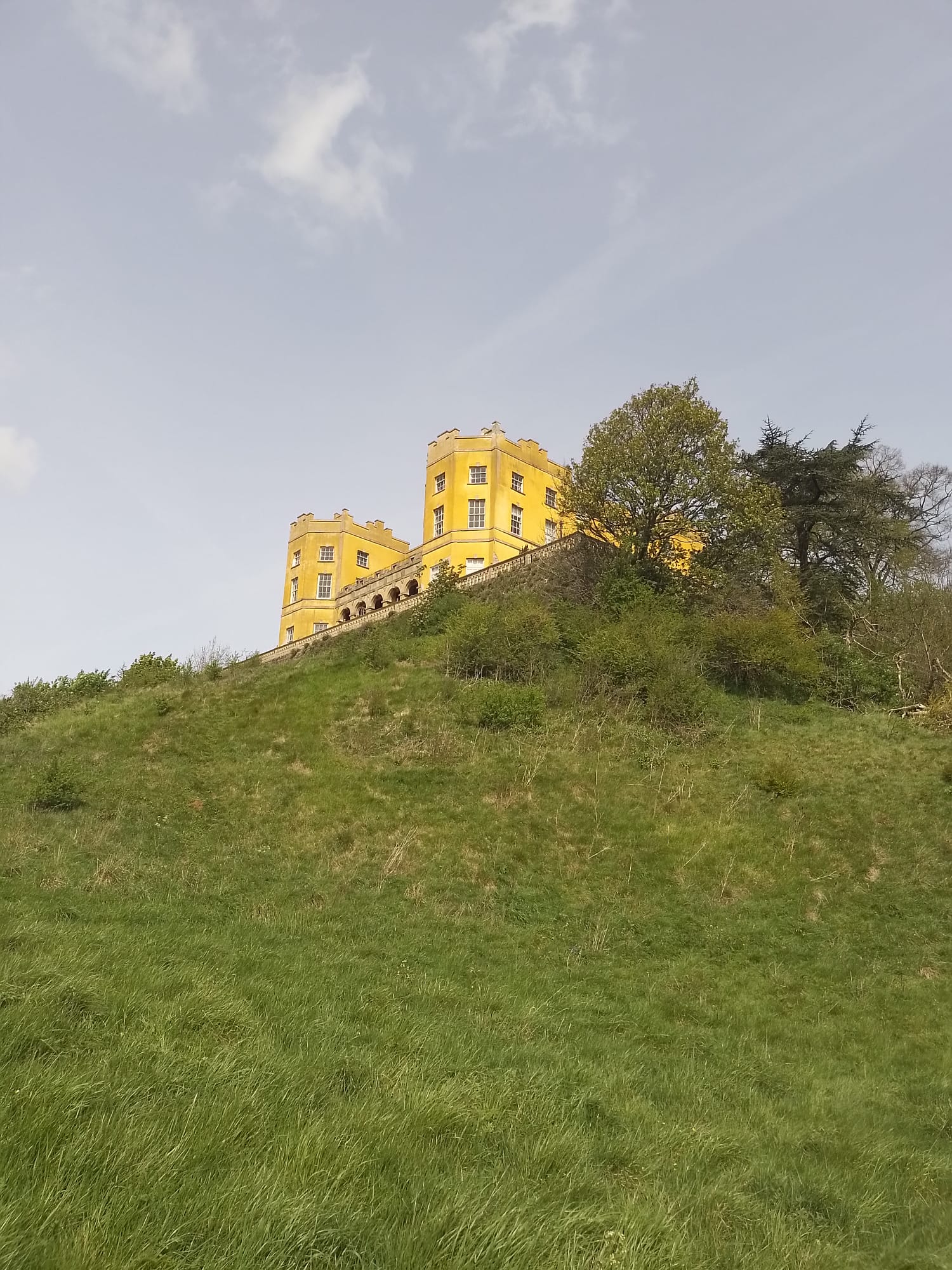view of the dower house from below. there is a divot in the hill which used to be used for cockfights