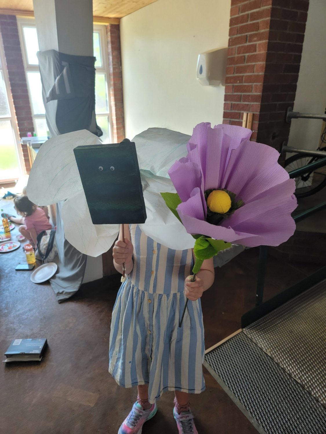 a child holding large tissue paper flowers in front of them