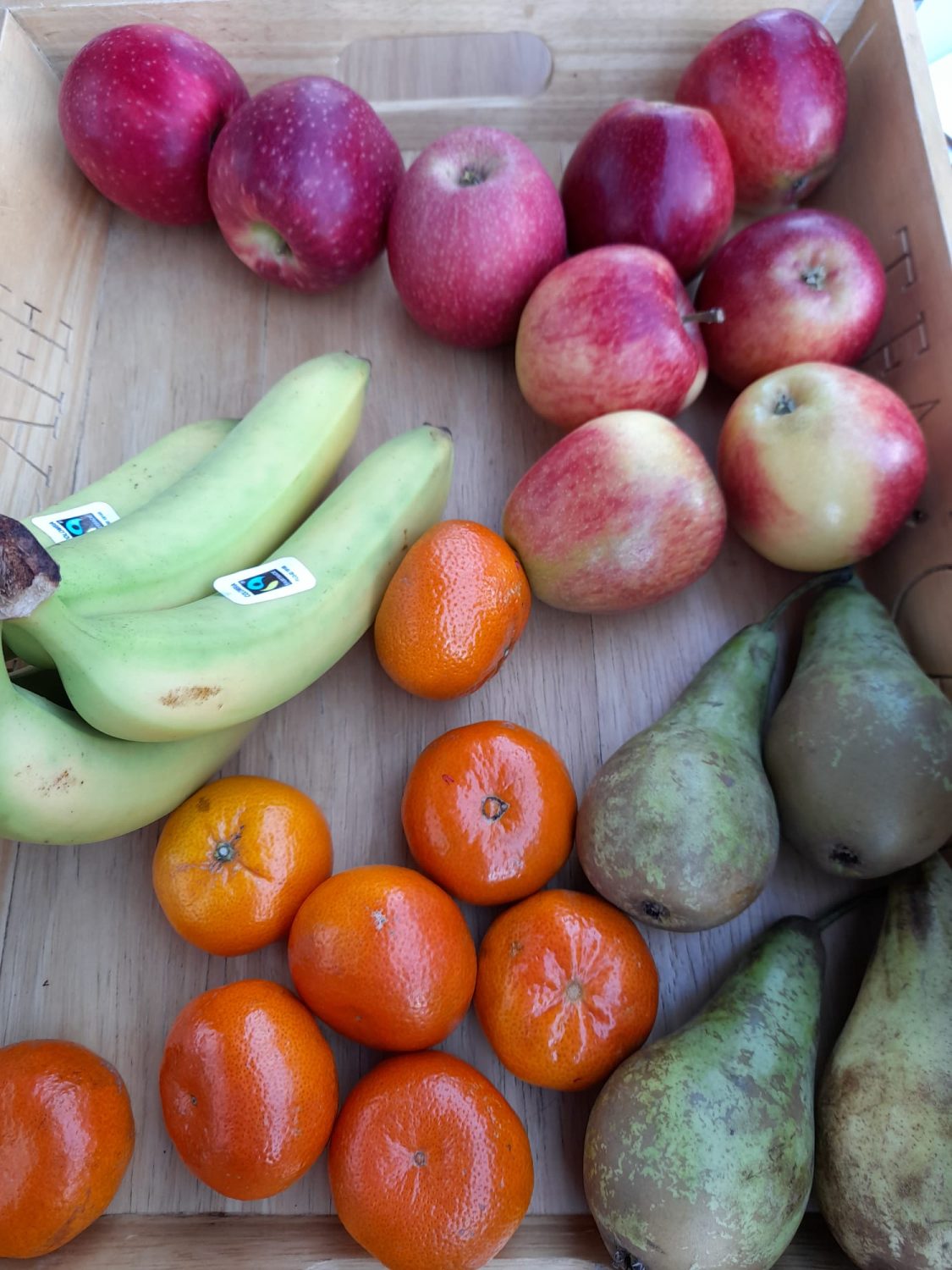 a wooden tray of bananas, satsumas, apples and pears