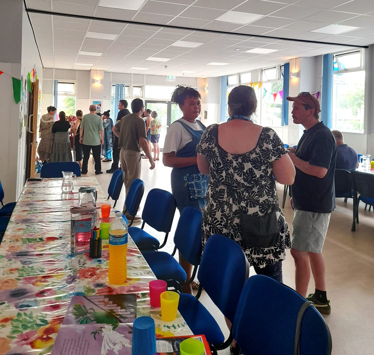 three or four bunches of people chat in the Hub, with long tables and tablecloths set up.