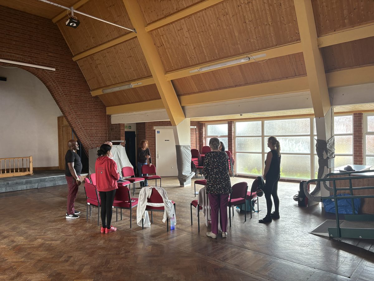 six or seven people stand around a circle of chairs